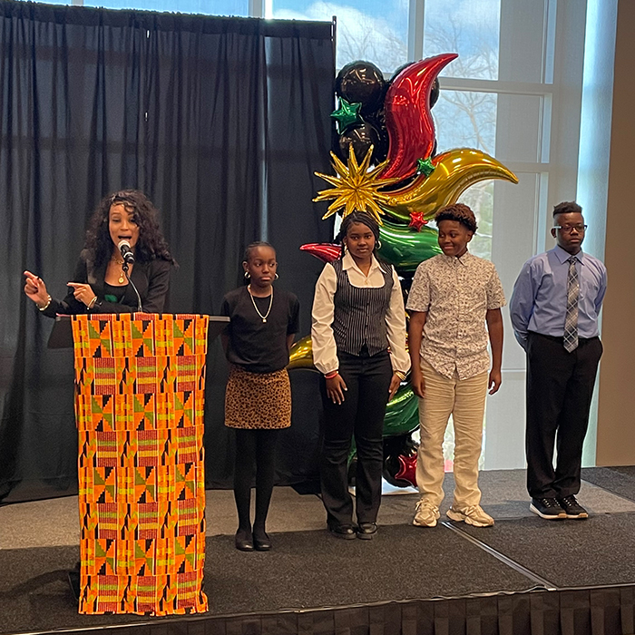 four students from local elementary school standing on event stage