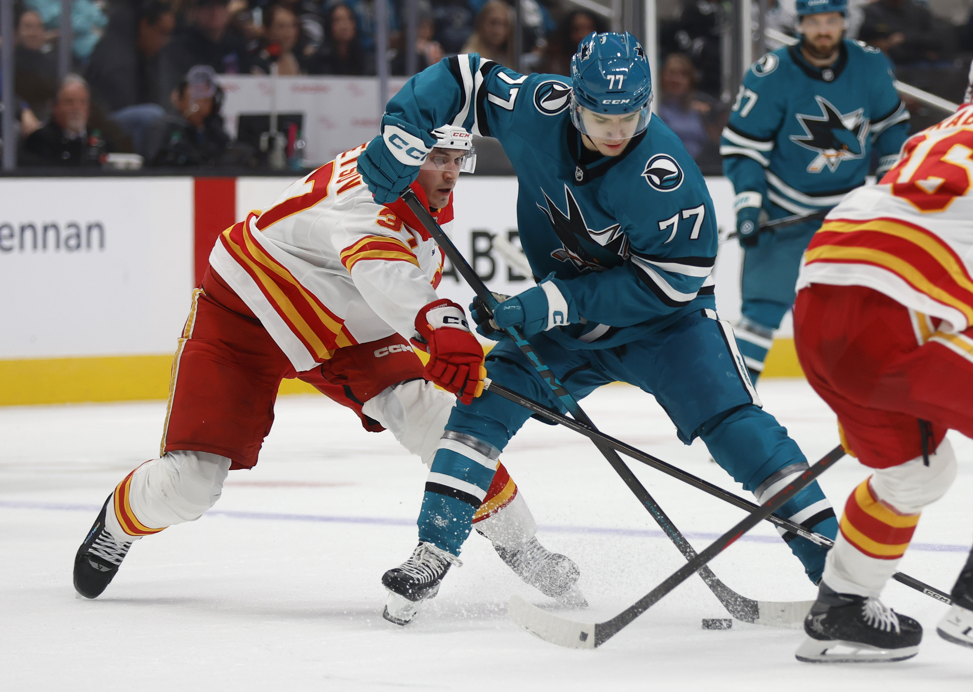 San Jose Sharks’ Michael Misa (77) fights for the puck...