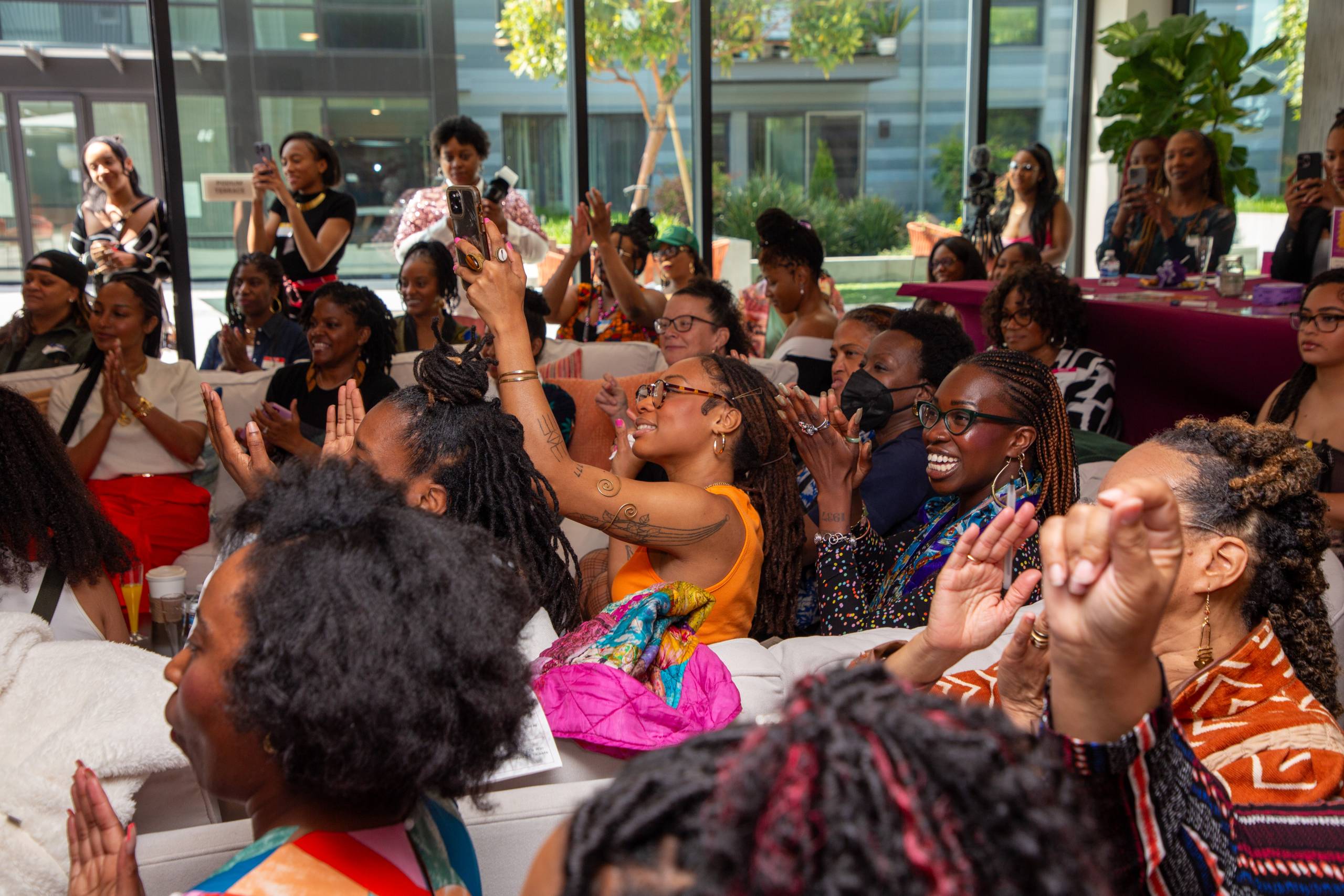 A group of Black women in an audience clap. 