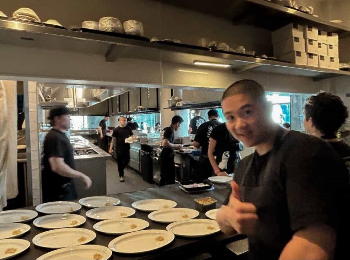 a man in a kitchen posing in front of dishes