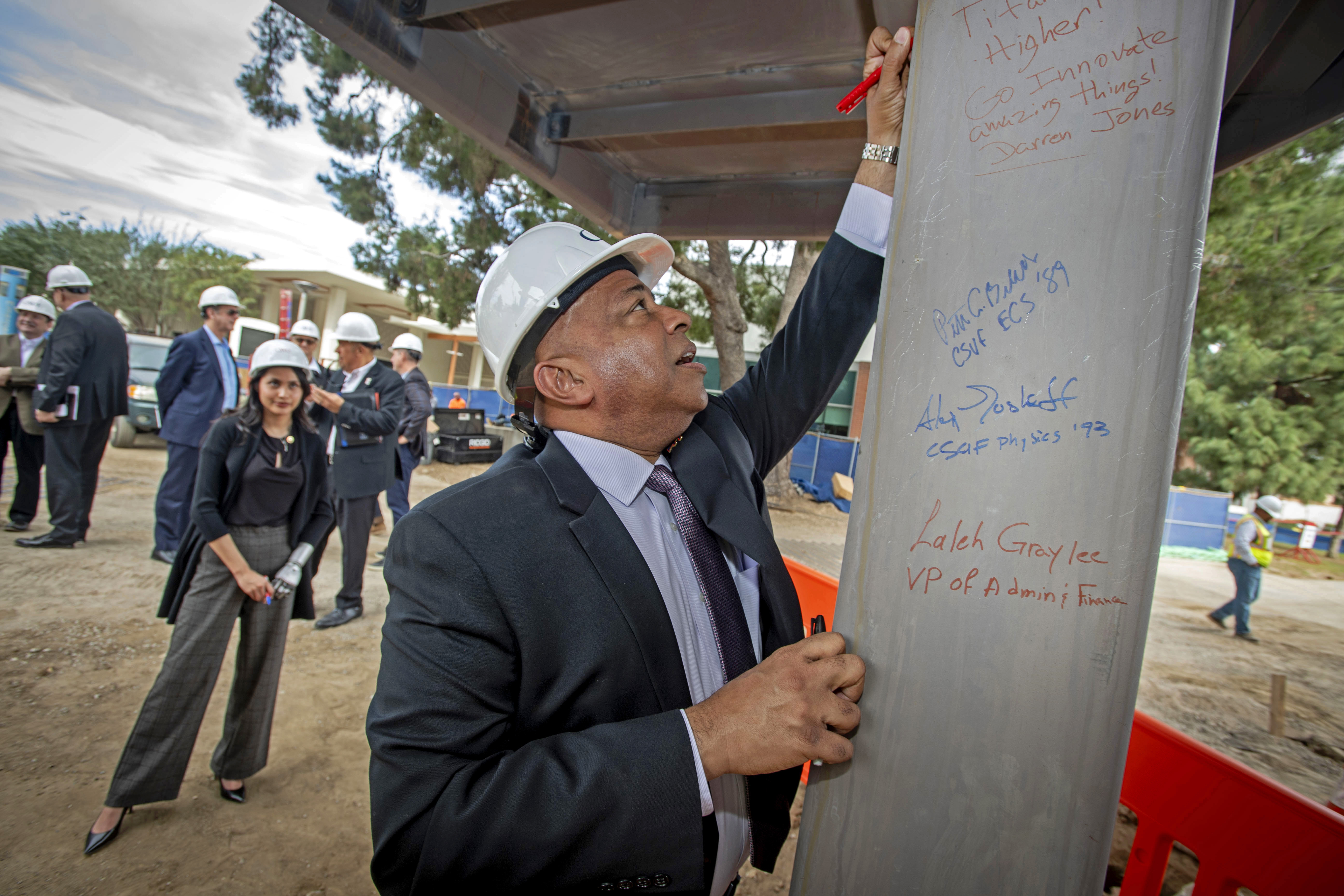 CSUF President Ronald Rochon puts his name on a beam...