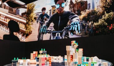 A group of building blocks on a table with buildings printed on them. Above them is a projected image of two boys on bikes wearing futuristic gear.