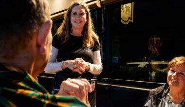 Cocktail server talking to customers at bar.