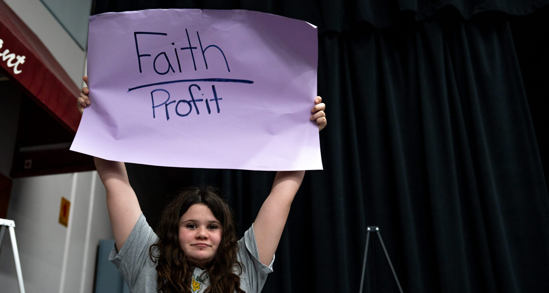 Bella Wood, 7th grade student at St. Patrick Academy, holding a sign at the merger meeting at St. Robert Catholic School on Feb. 12, 2026. Photo by Denis Akbari.