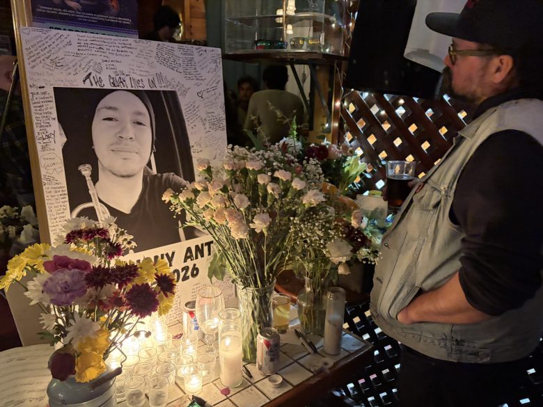 A man looks at a memorial on a table with photo, flowers and candles