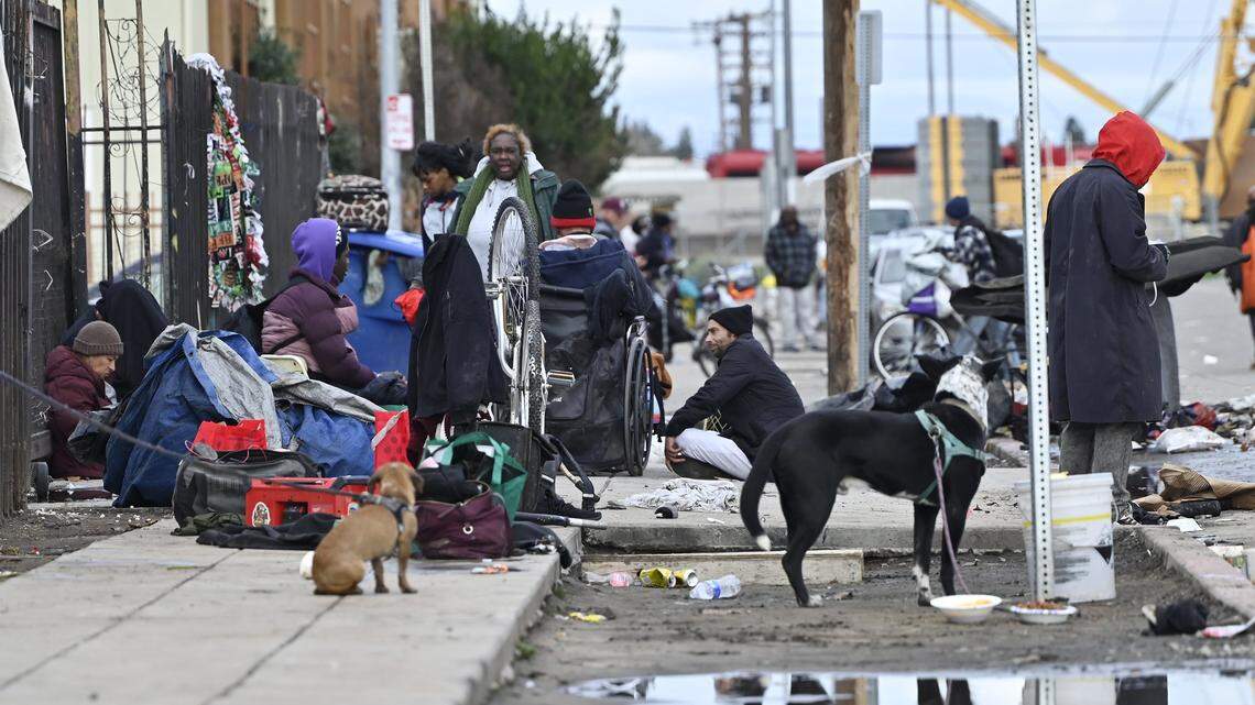 Homeless gather outside the Poverello House entrance on Santa Clara Street Friday, Dec 26, 2025 in Fresno.