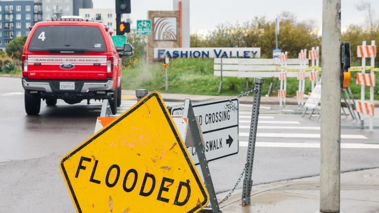 Flooded intersection with caution signs and a San Diego Fire-Rescue truck.