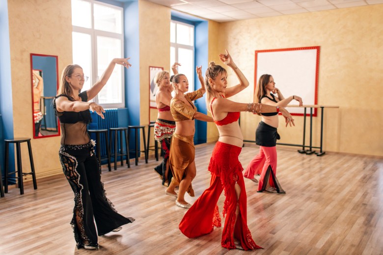 Group of beautiful women dancing in front of mirror at the belly dance training.