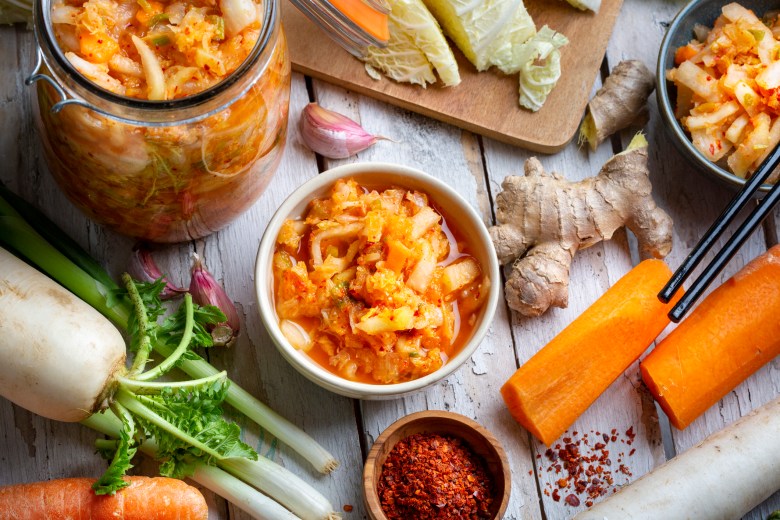 Bowl of kimchi sitting amid ingredients used in its making