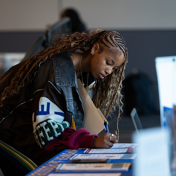 event attendee filling out papers at university booth