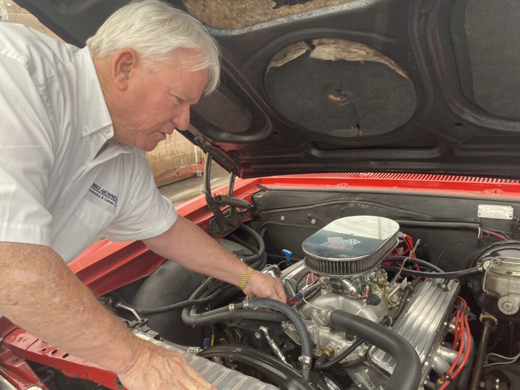 A man stoops over a car engine.