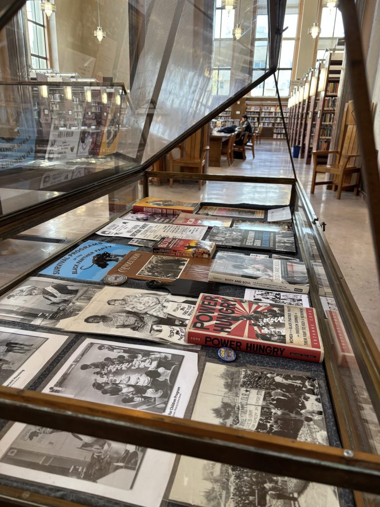 A display case is open to reveal several historic photos, books and other materials