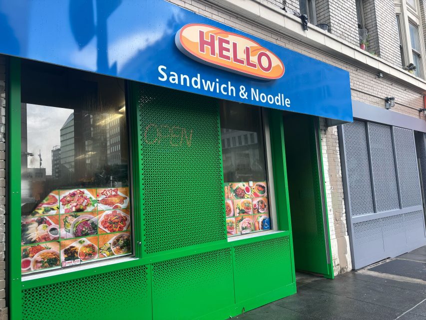 The storefront of "Hello Sandwich & Noodle" features a blue sign, green exterior, and food photos displayed in the window. An "OPEN" sign is visible inside.