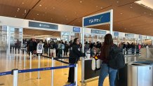 A TSA officer helps a traveler maneuver security lines, Sunday, in Terminal 1, February 22, 2026.