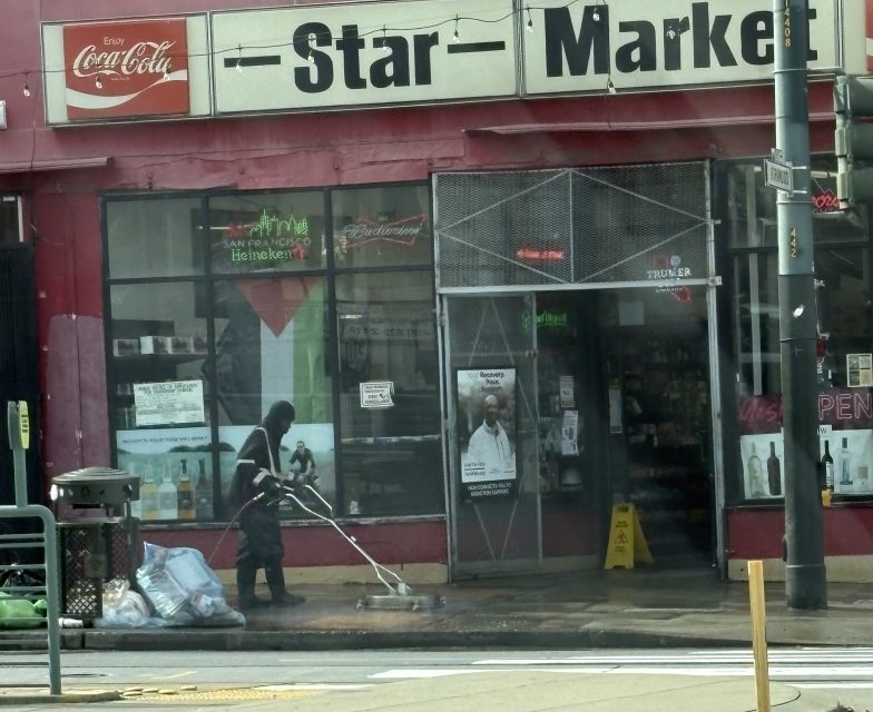 A person power washes the sidewalk outside a store called Star Market, with garbage bags and bottles visible near the entrance.