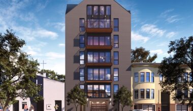 A modern six-story apartment building with balconies, located between two older residential homes, with people walking and cars parked on the street.