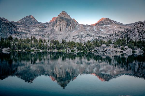 Mountains reflect in the tree-lined water of the lake