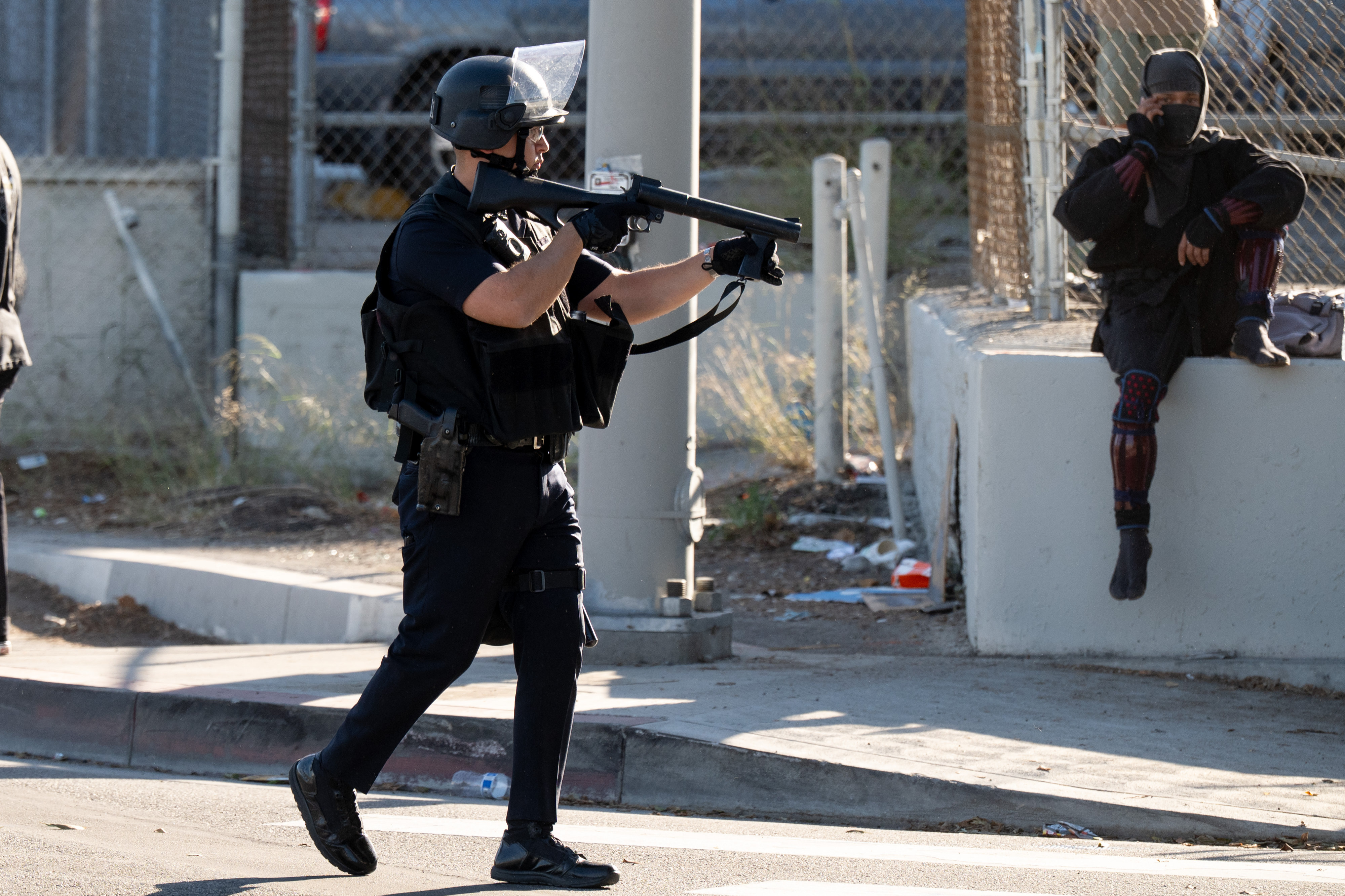A LAPD officer aims a less lethal gun at a...