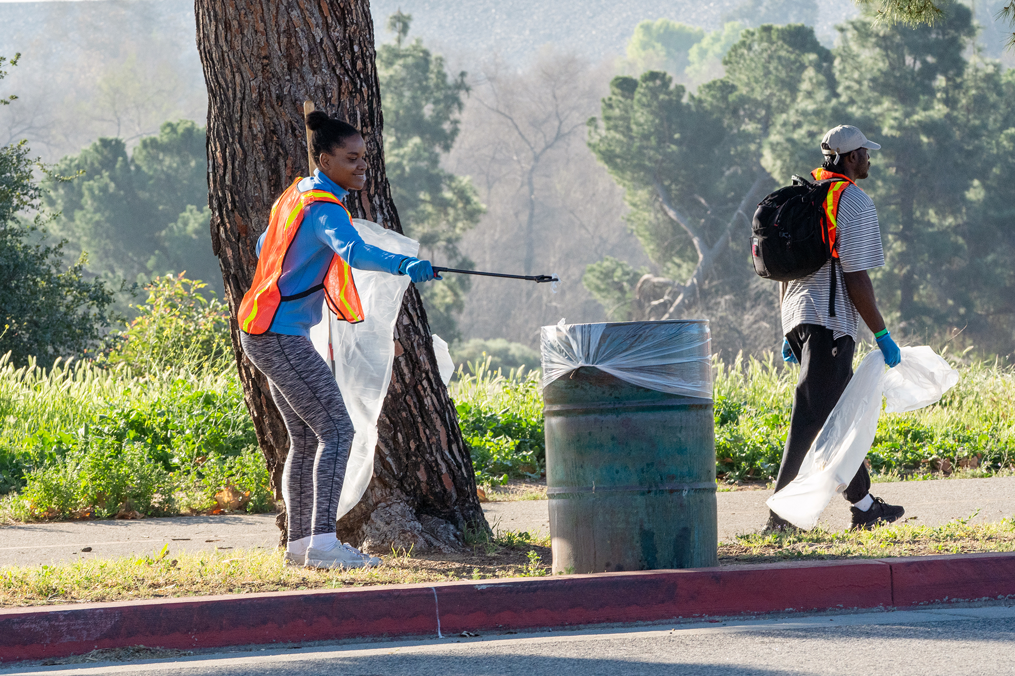 A volunteer deposits a piece of litter into a trash...