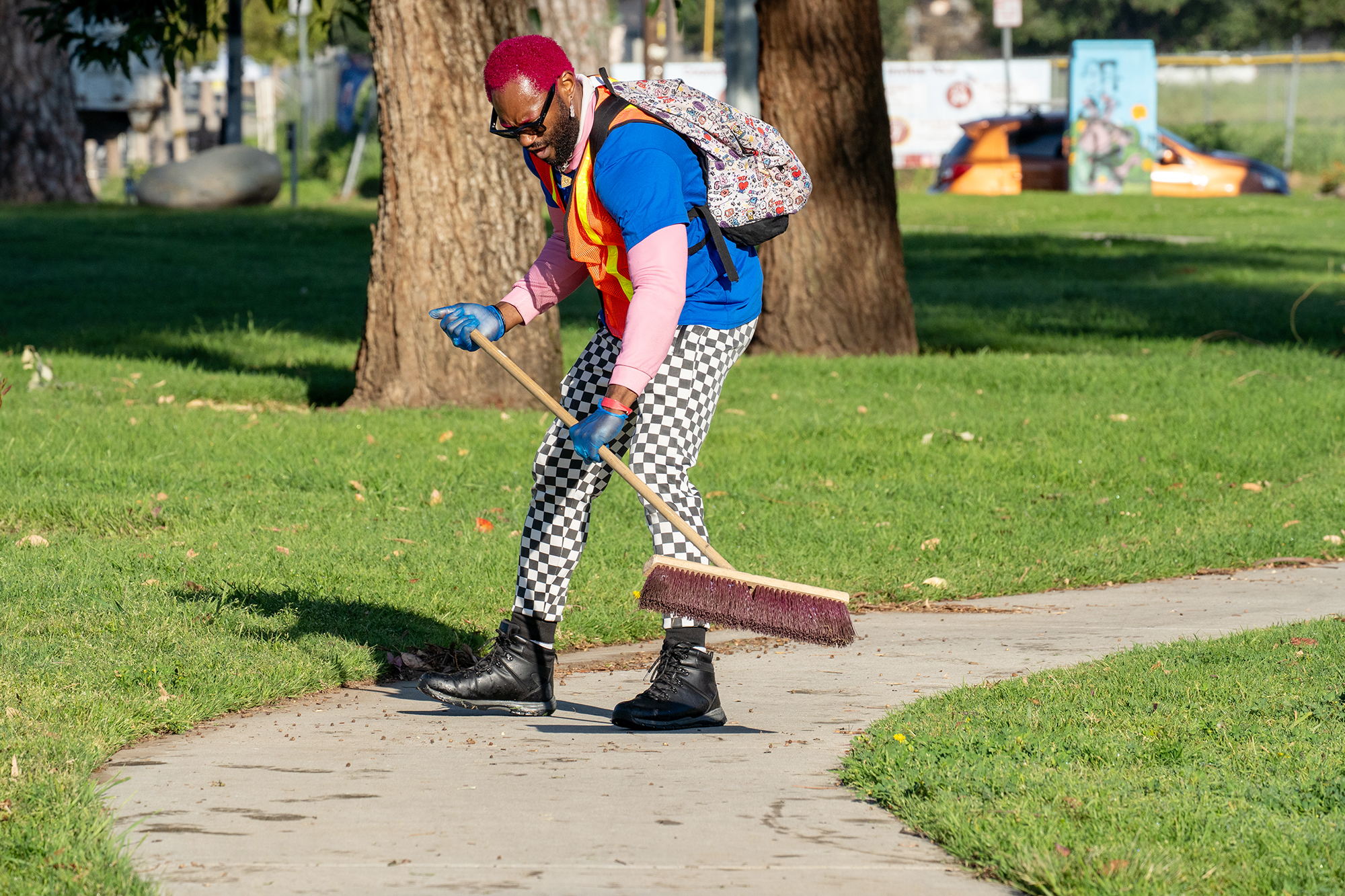 Volunteer Jame Tabor sweeps a sidewalk near the Hansen Dam...
