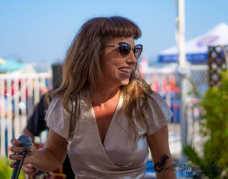 A woman wearing sunglasses and holding a microphone outdoors