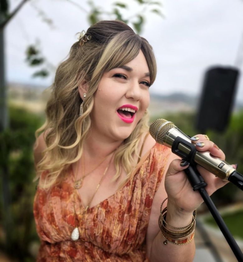 A woman holding a microphone and singing outdoors