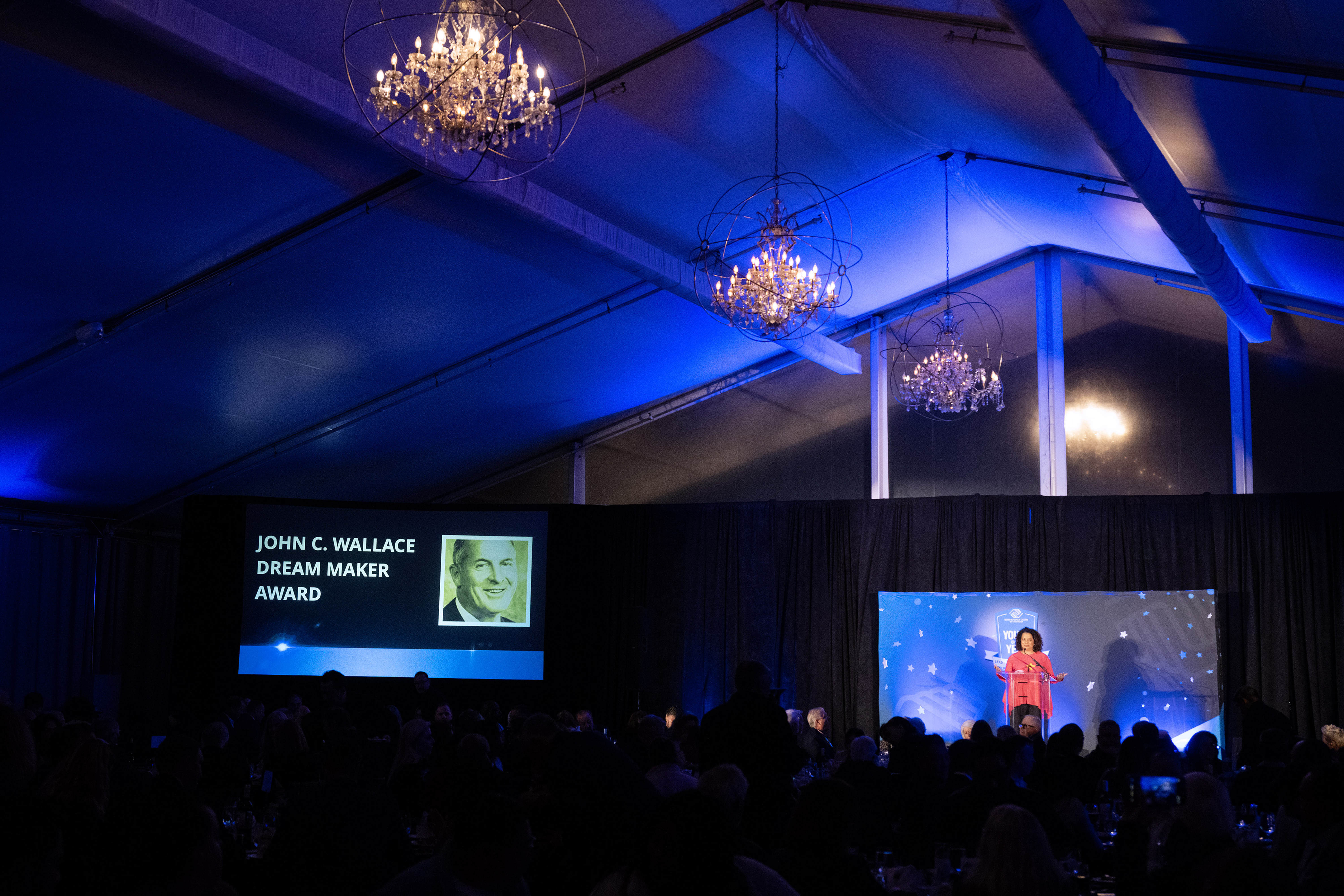 Board member Michaela Pereira welcomes the audience to the Boys...