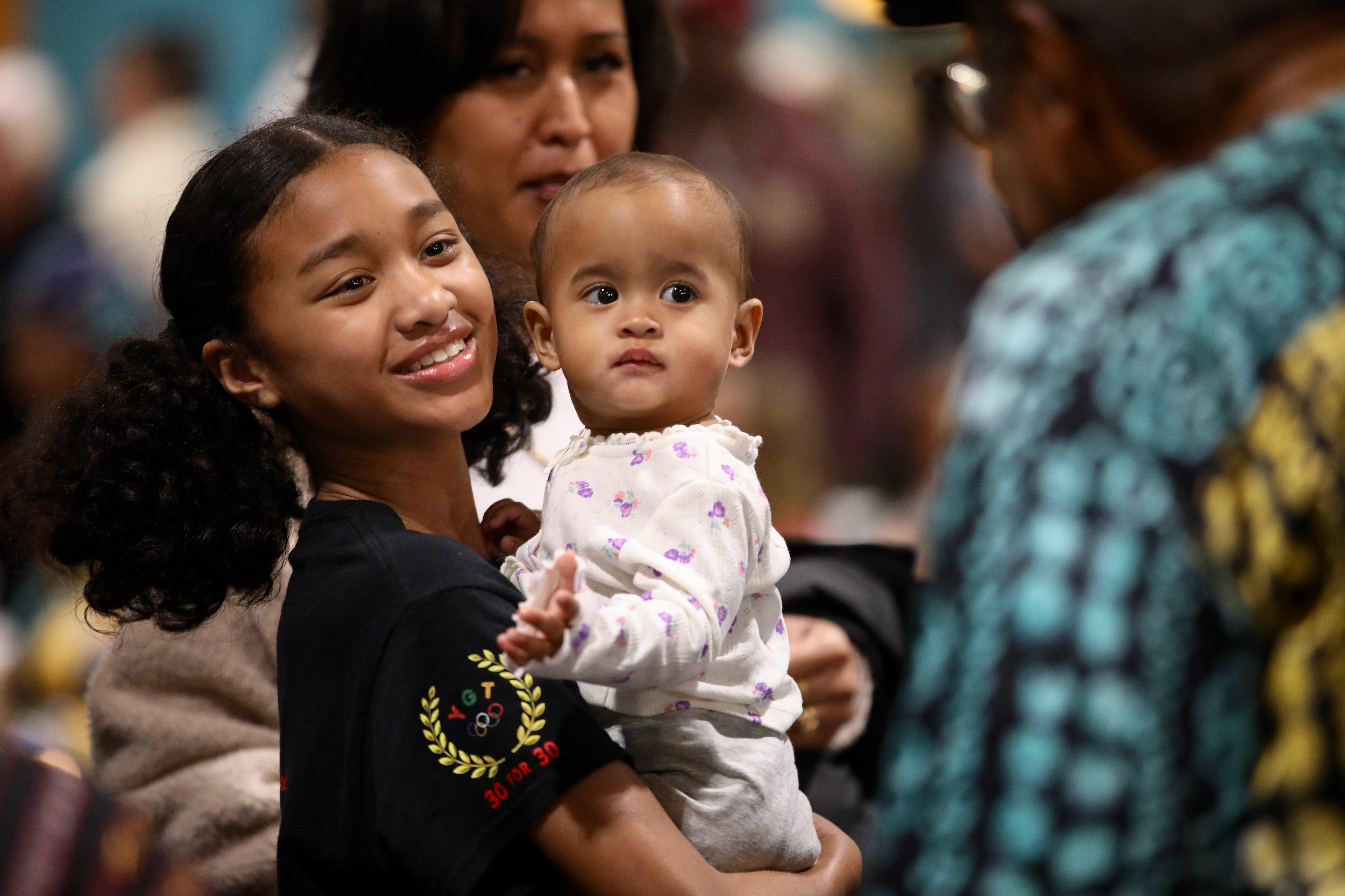 Dancer Helena Sedler holds Kennedy, 1, during a Black History...