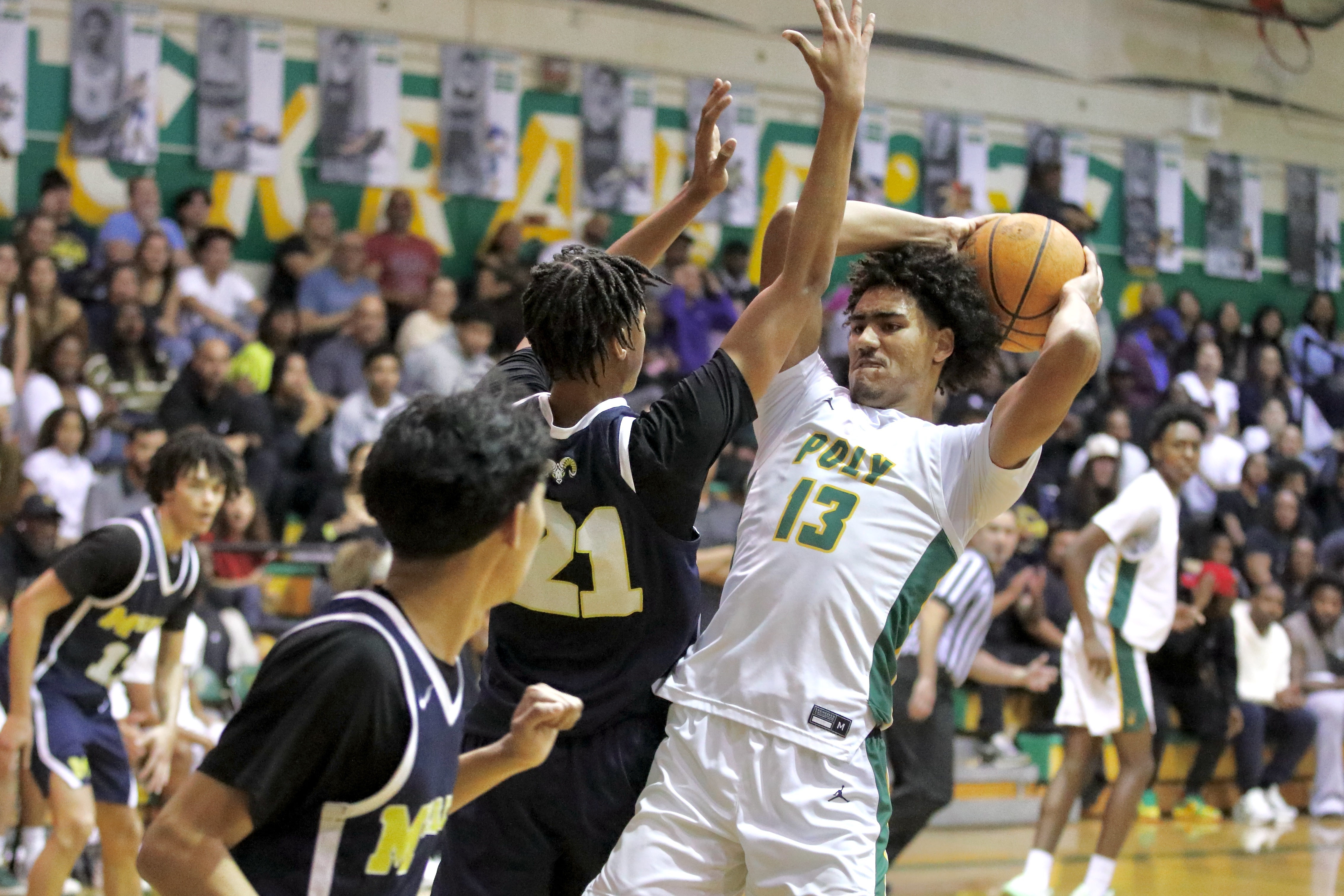 Long Beach Poly senior center Jonas Oware secures a rebound...