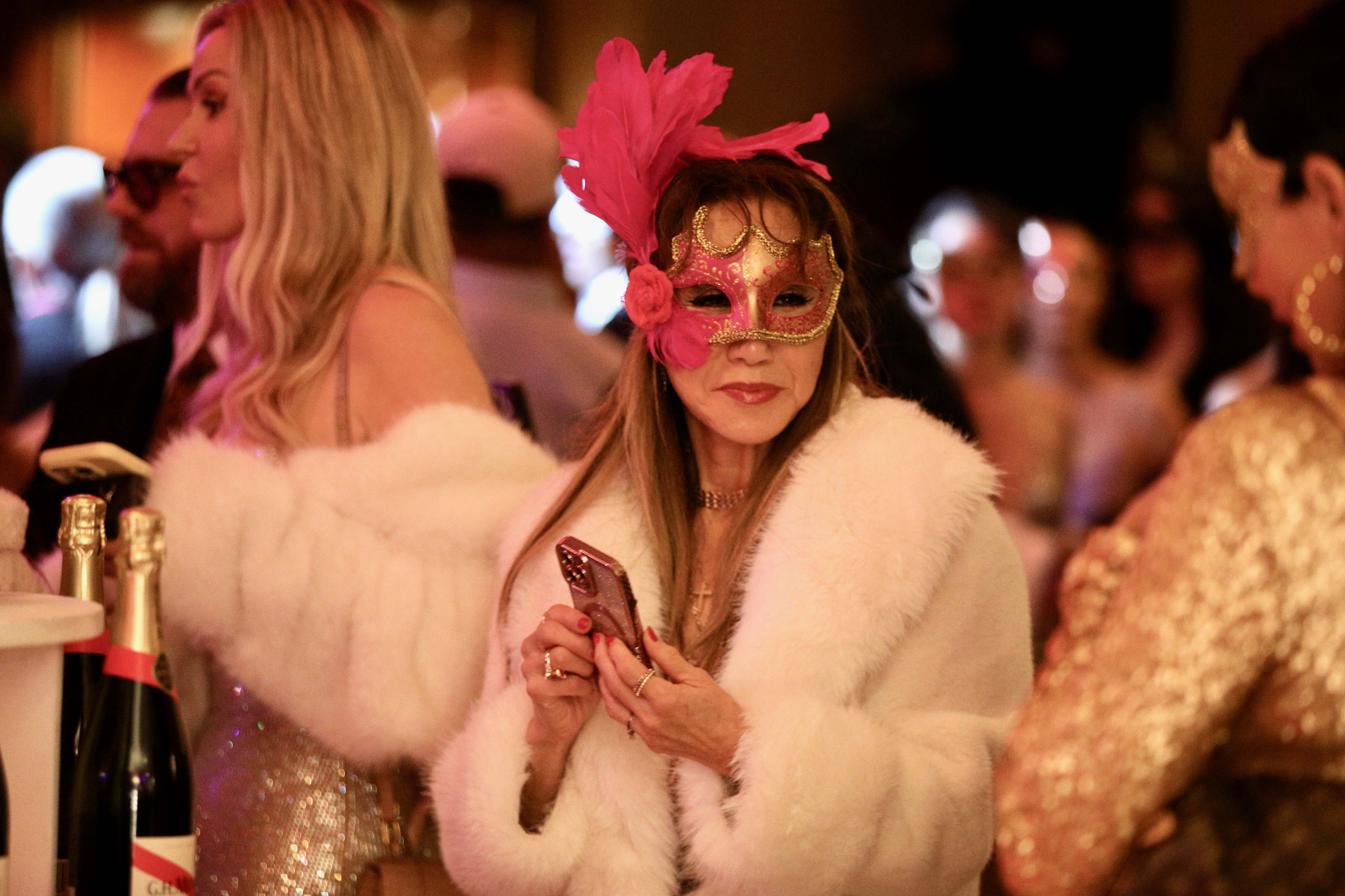 A mask-wearing reveler rings in the new year on the...