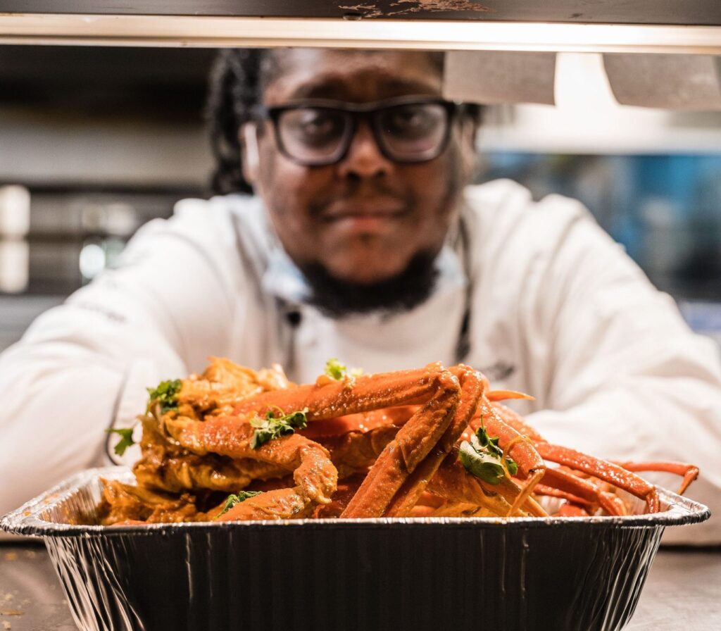 Fried food in the foreground with Chef Q blurred in the background