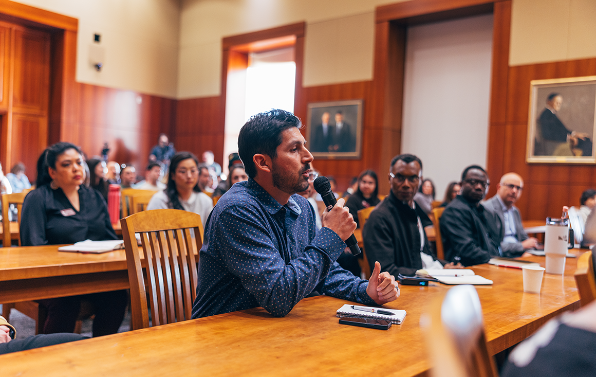 An audience member asks a questions on a microphone in a crowded lecture hall.