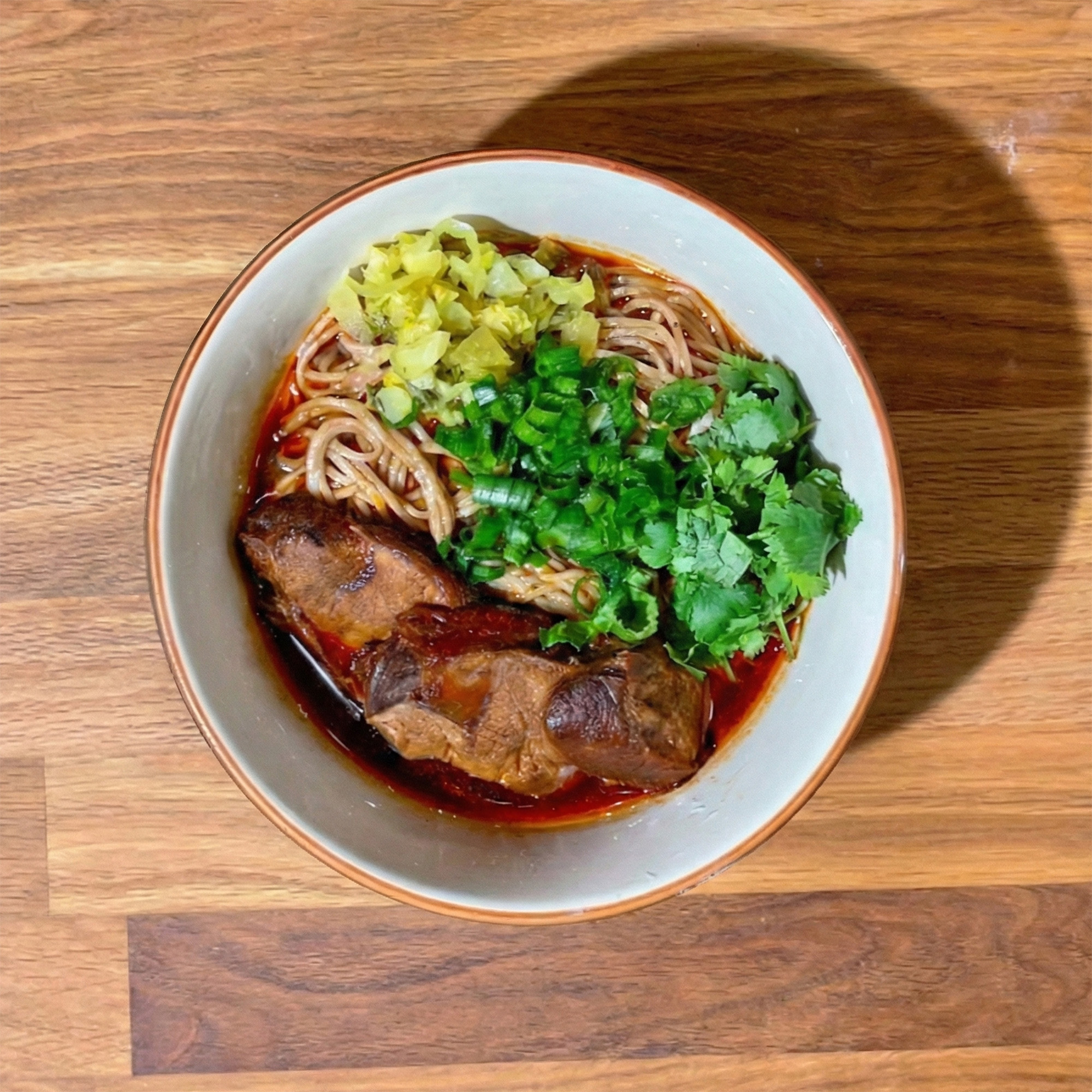 Overhead view of a bowl of beef noodle soup.