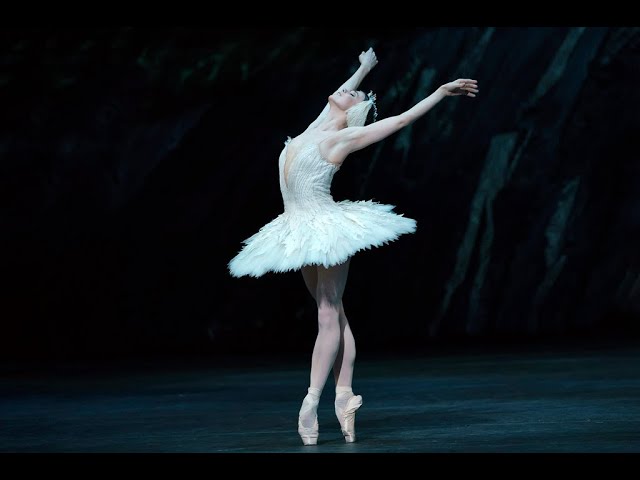 Onstage, Natalia Osipova stands on pointe and arches up and back, her arms lifted like wings. She wears a white tutu with feathers and a headpiece, and she closes her eyes and parts her lips with emotion.