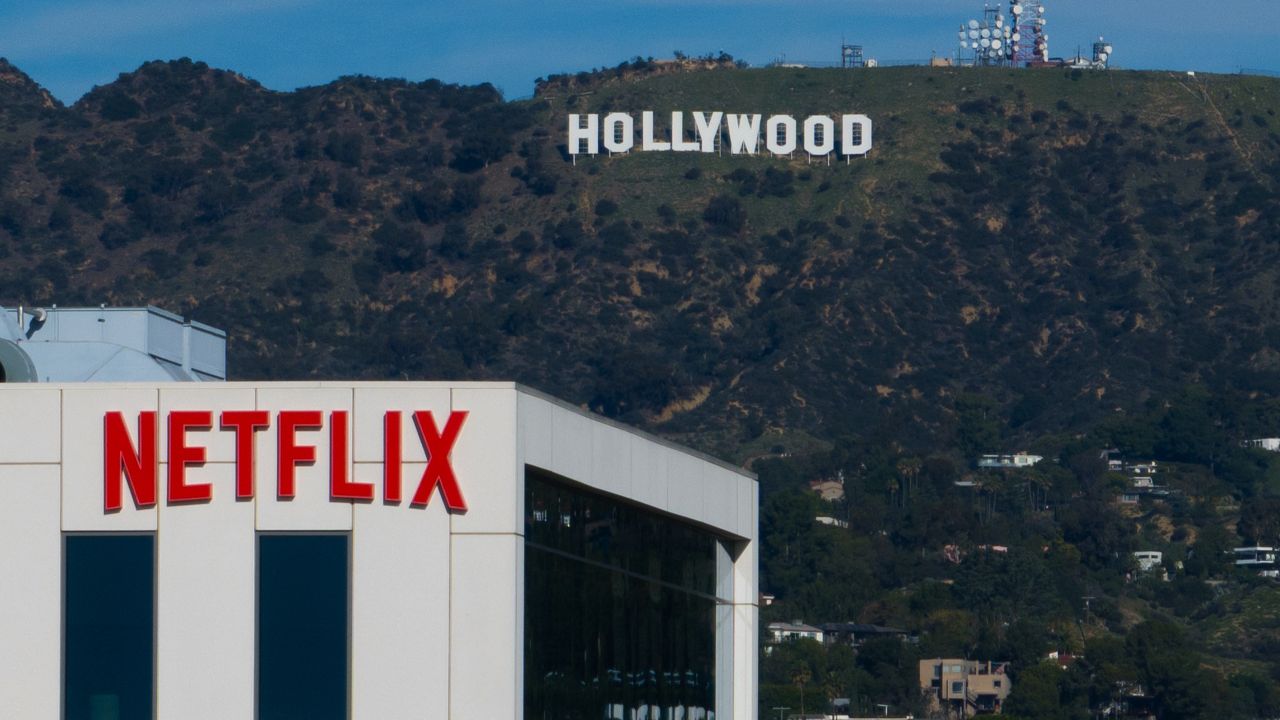 A Netflix sign is displayed atop a building in Los Angeles, on Dec. 18, 2025, with the Hollywood sign in the distance. (AP Photo/Jae C. Hong, File)