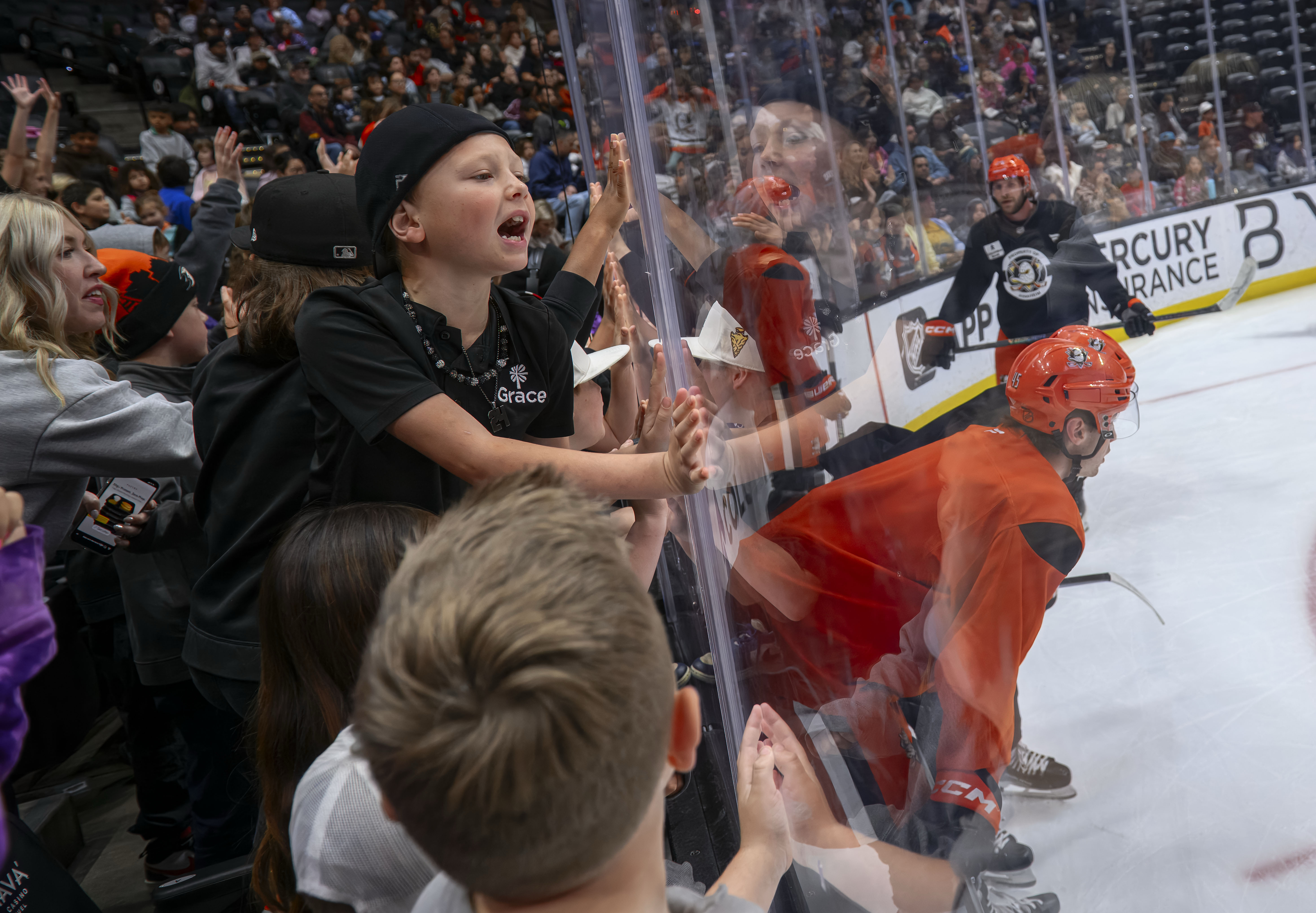 An elementary school student cheers Anaheim Ducks players as they...