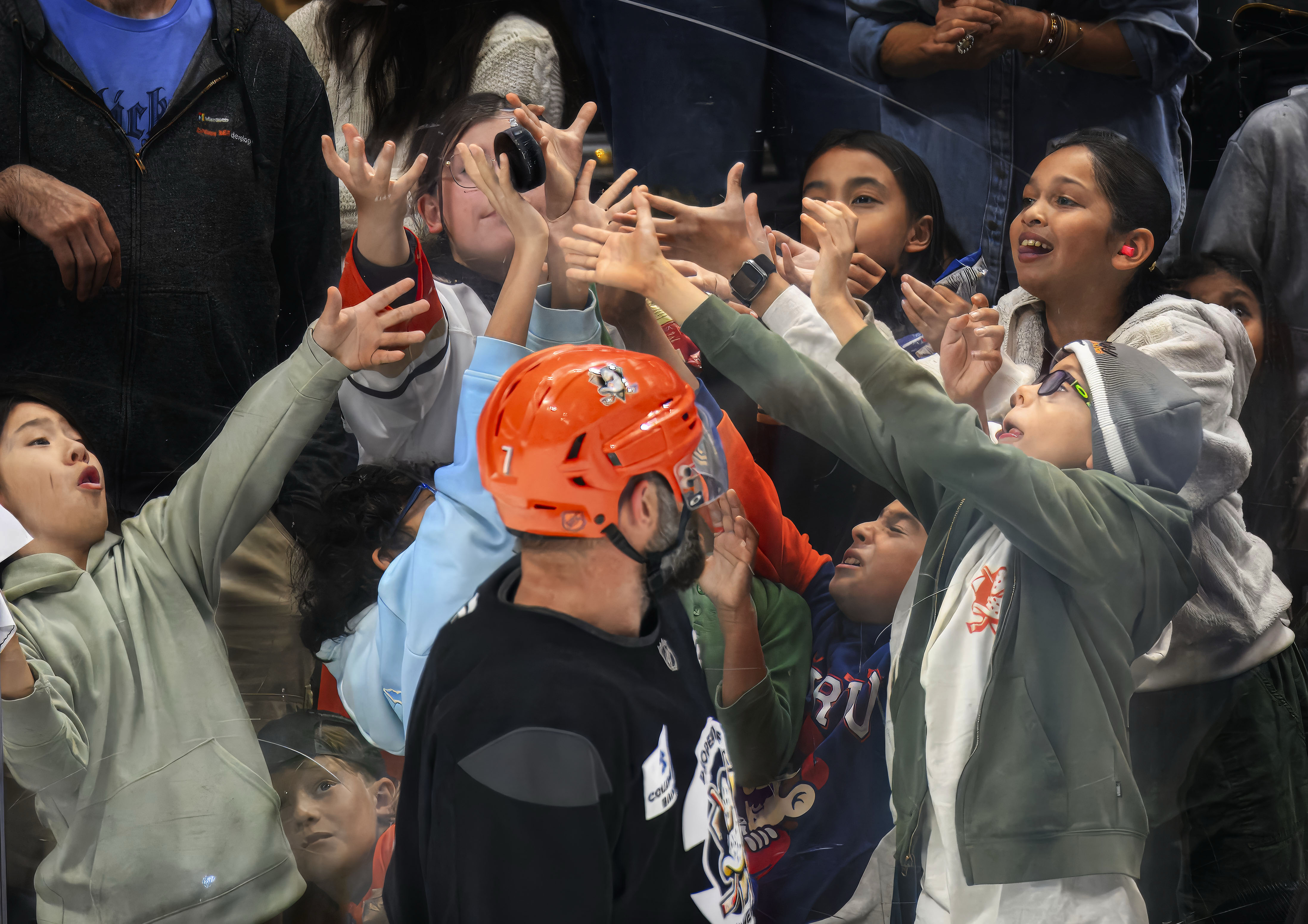 School Kids reach for a puck thrown to them by...