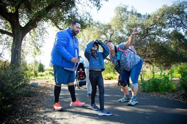Tina Stoner, chapter president of the Pomona Valley Bird Alliance, helps Viviana Espinoza, 7, and her father William, 45, both of Alhambra, look for birds during a bird walk, on Sunday, Feb. 1, 2026, at the California Botanic Garden in Claremont. (Photo by Stan Lim, Contributing Photographer)