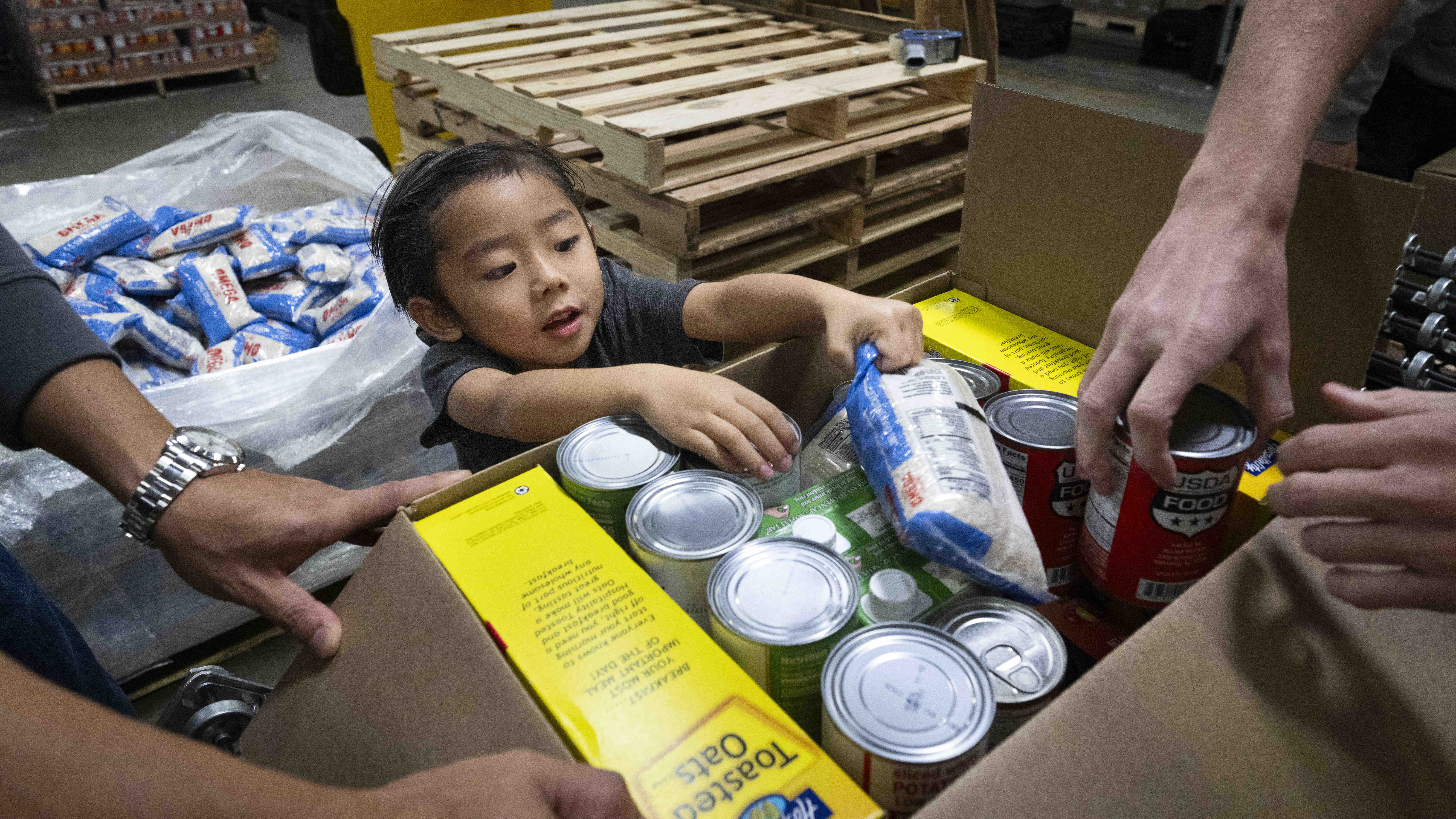 Five-year-old Hunter Yee helps load food boxes during the Martin...