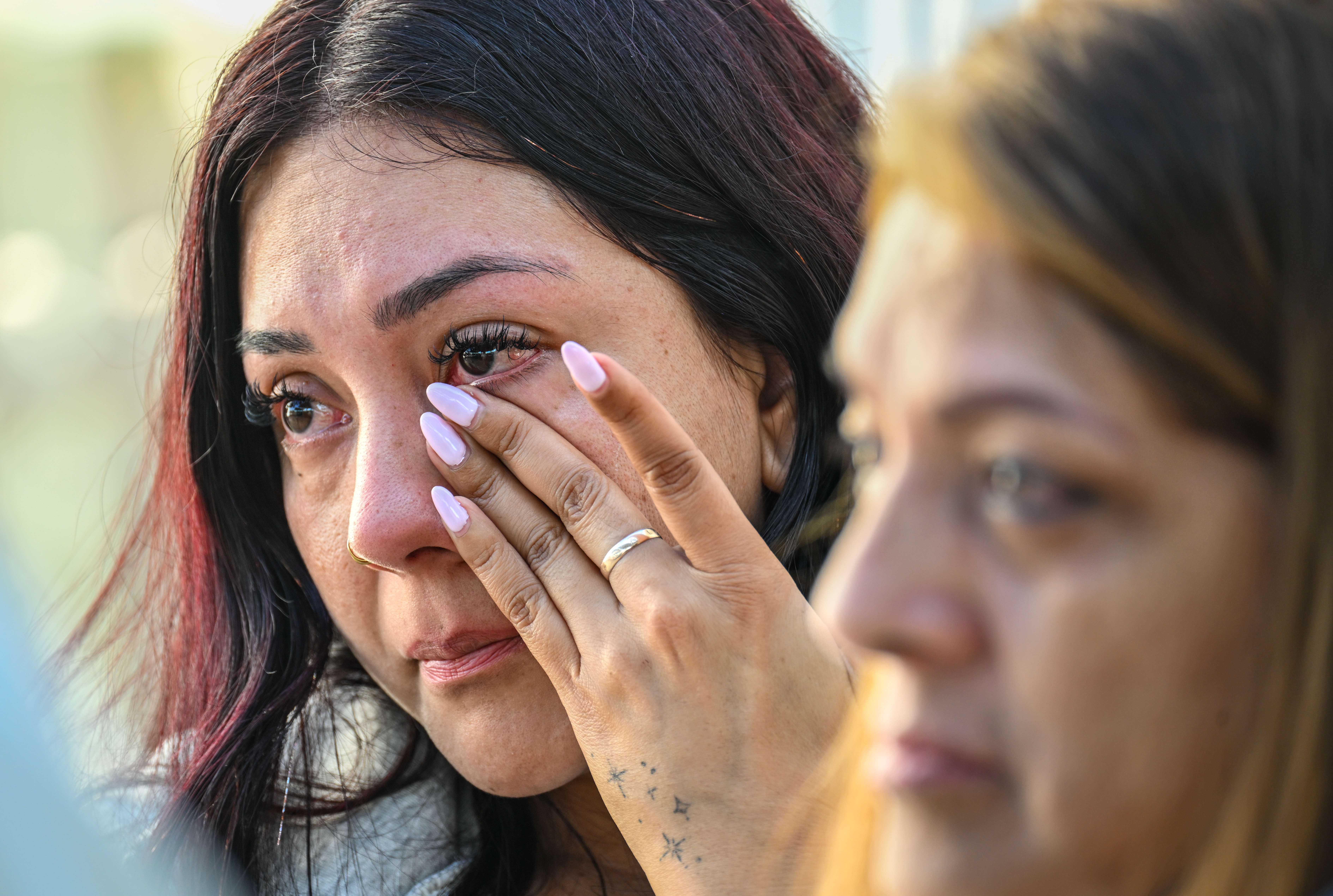 Karina Perez wipes a tear from her eye as she...