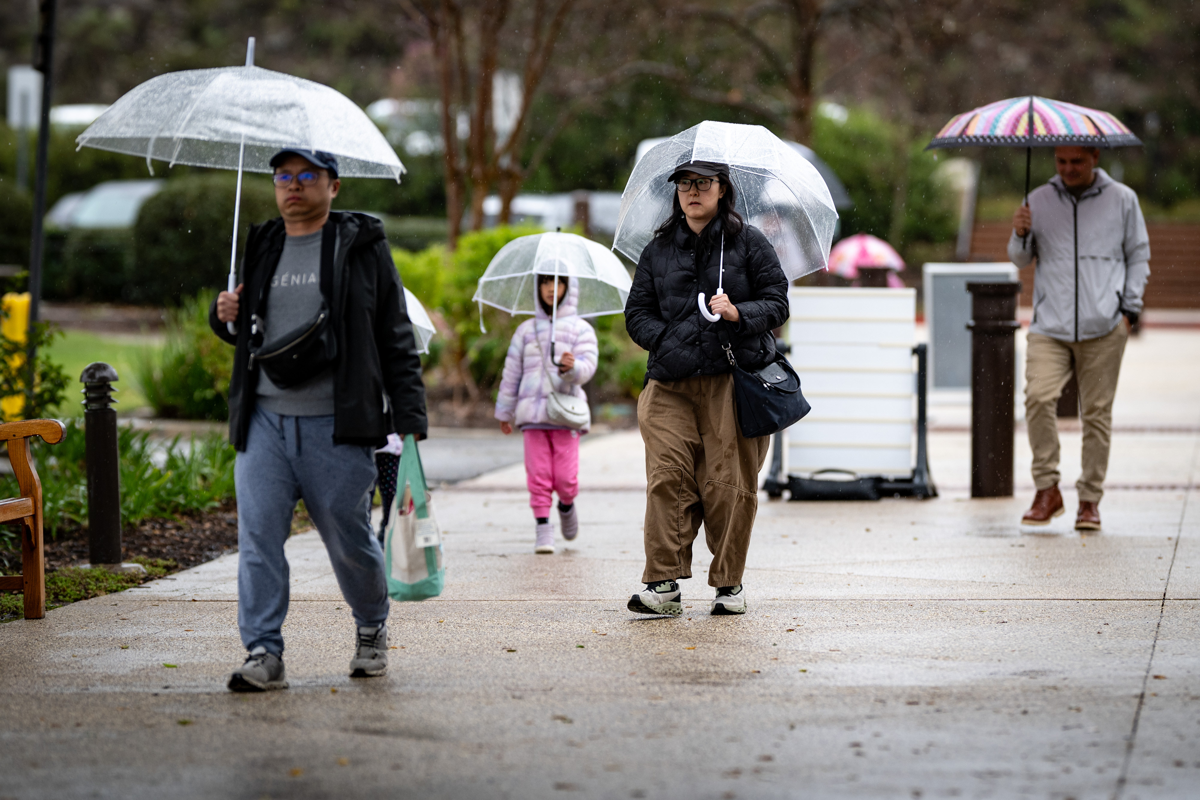Visitors don umbrellas during a downpour at the Ronald Reagan...