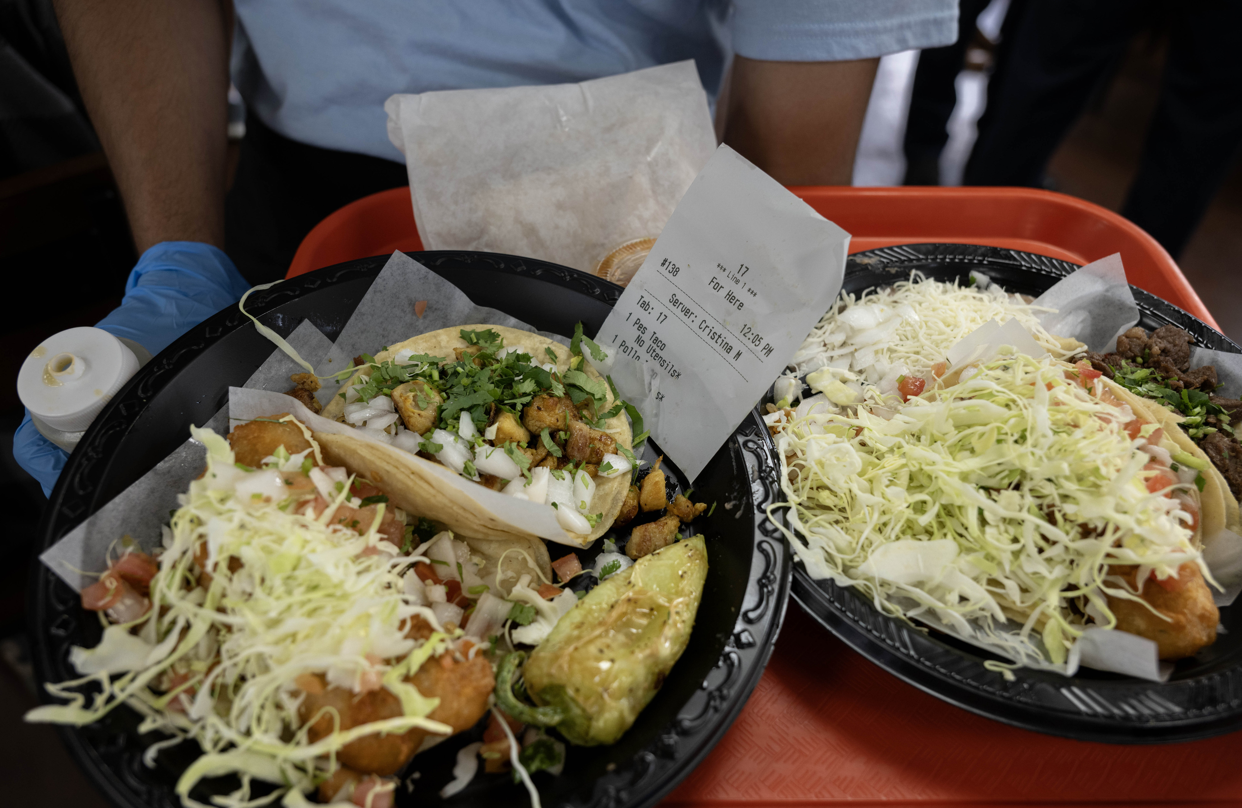 Taco Nazo employee Angel Dolmos serves tacos to lunch-hour patrons...