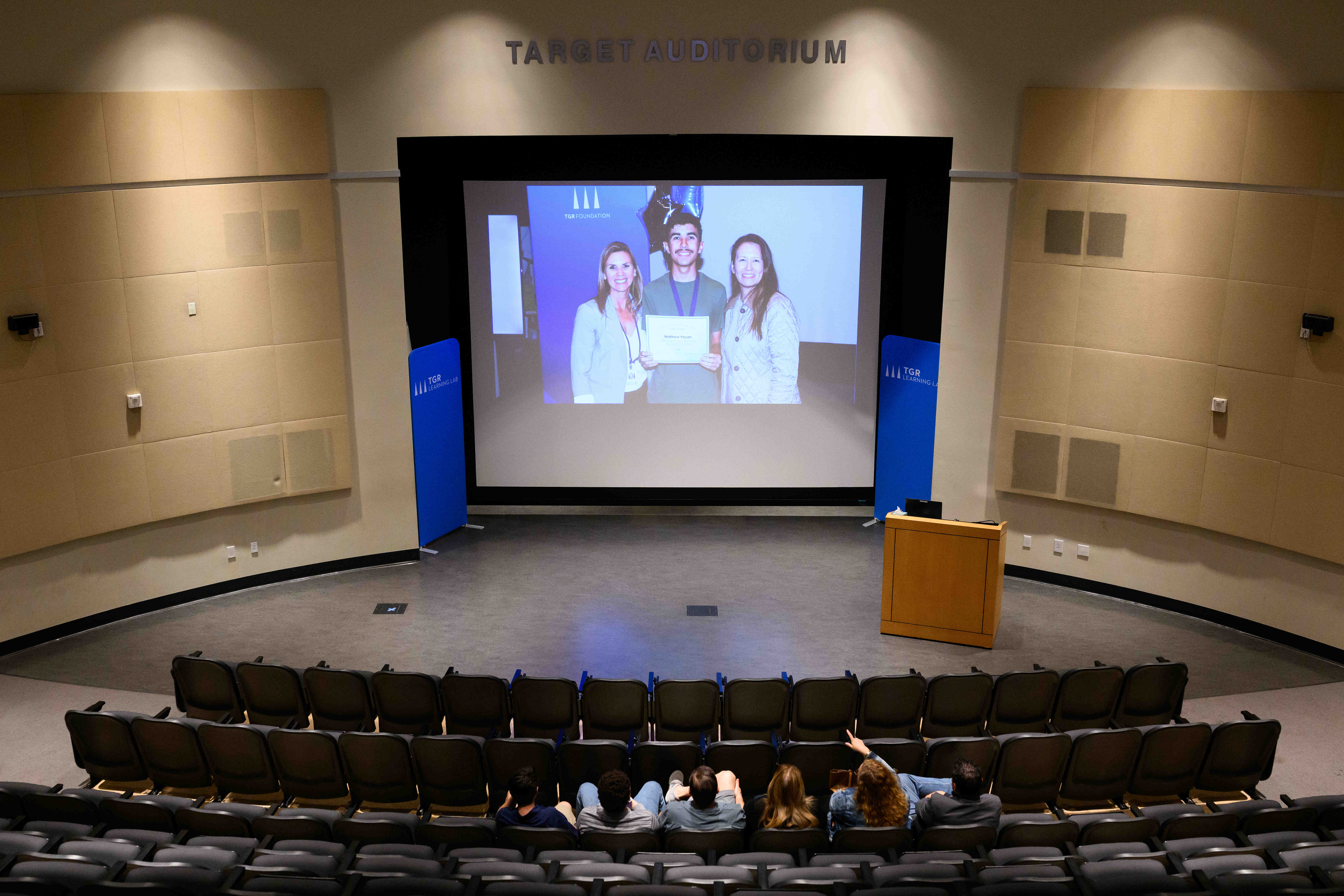 People watch a presentation in the auditorium during an event...