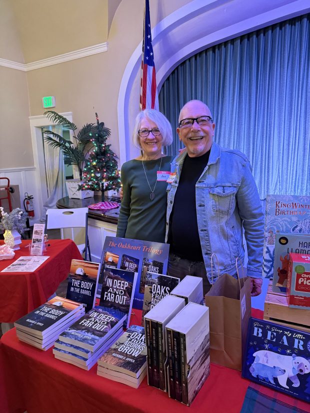 Richard Opper and his wife, Ann Poppe, show copies of all three of his Mona Oakheart novels at a Point Loma Assembly event. (Provided by Richard Opper)