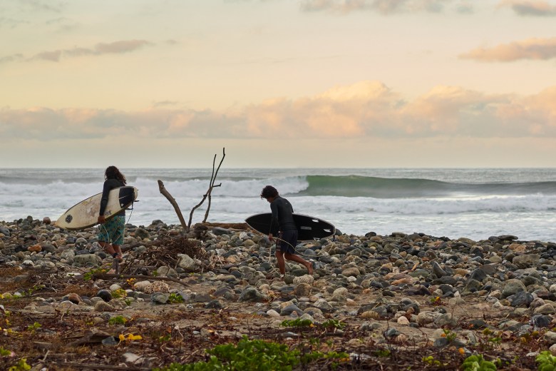 Two surfers walk along the beach for the filming of Haagua. (Photo courtesy Scott Soen)