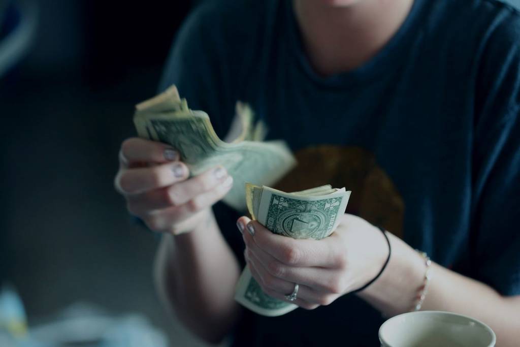 Photo of hands counting U.S. dollar bills.