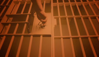 Bars from a jail cell frame a door being locked.