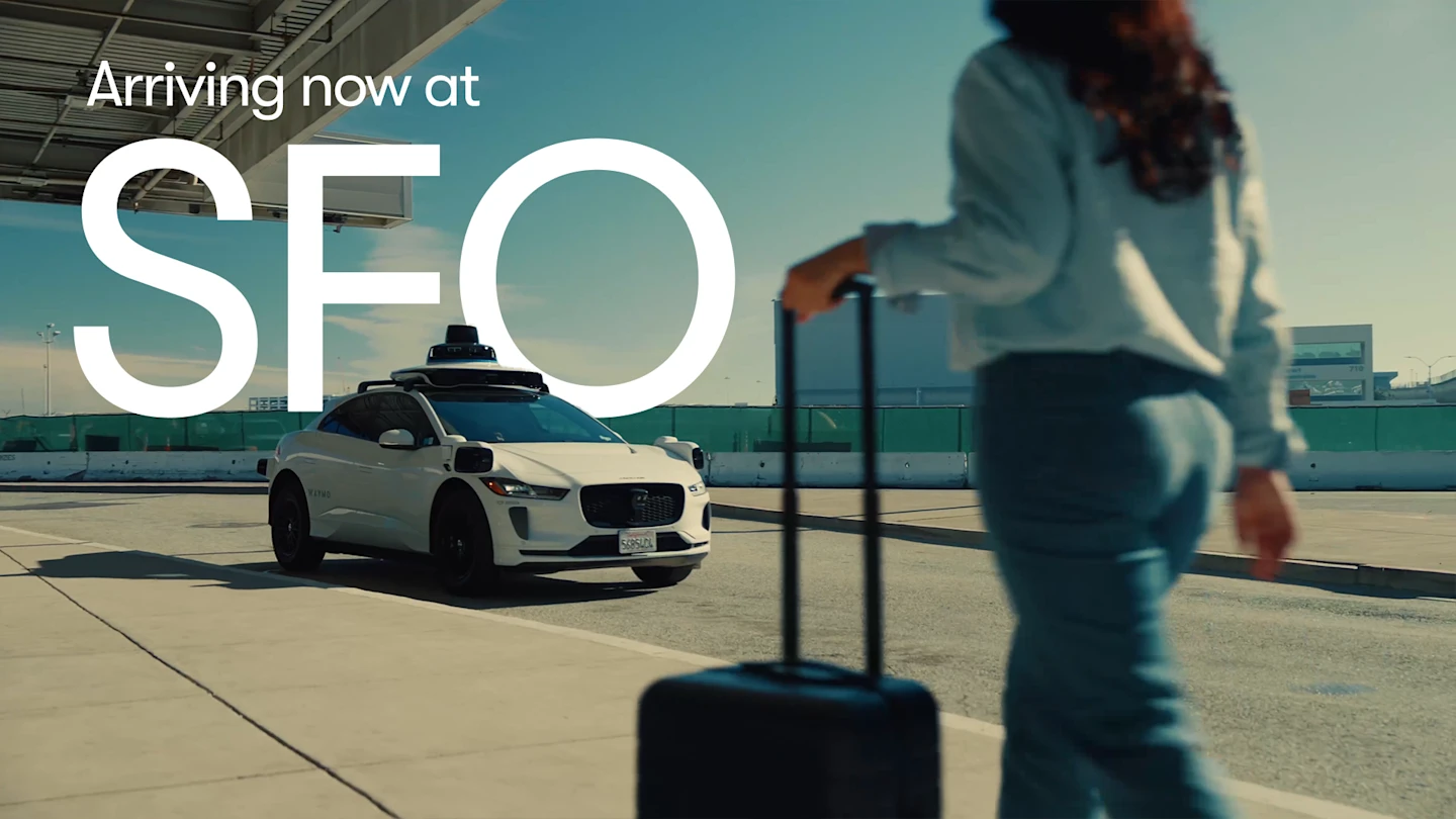 A woman walking toward an autonomous car with luggage