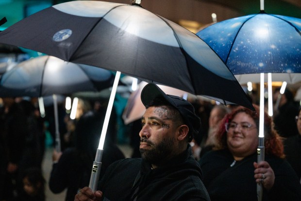 Participants march with umbrellas printed with aerial photographs at City Hall in San Jose, Calif., on Saturday, Jan. 31, 2026. (Thien-An Truong for Bay Area News Group)