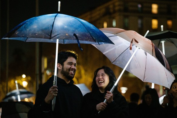 Participants stand with umbrellas printed with aerial photographs at City Hall in San Jose, Calif., on Saturday, Jan. 31, 2026. (Thien-An Truong for Bay Area News Group)